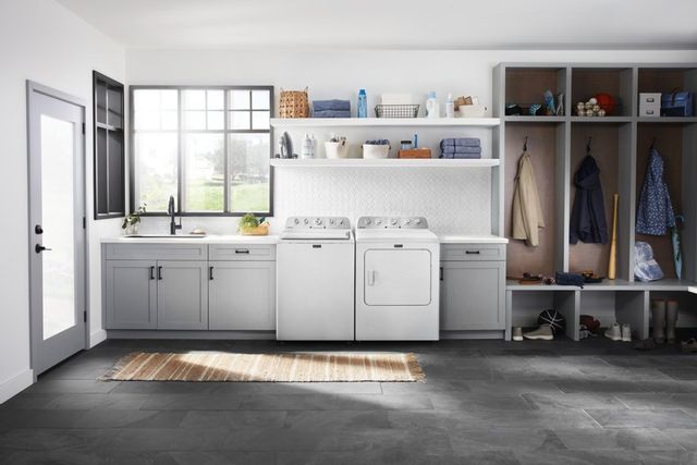 Maytag electric dryer and top load washer in a large, sunny laundry room