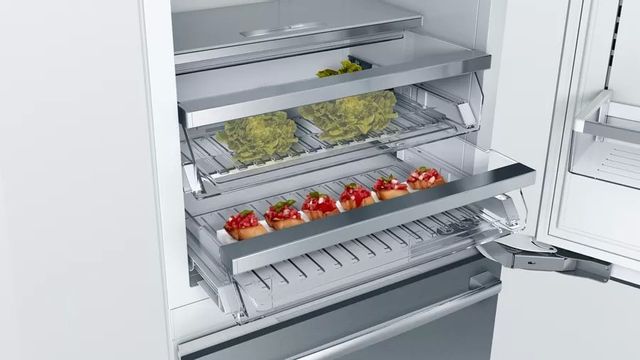 The interior drawers of a bottom freezer refrigerator with food stored within