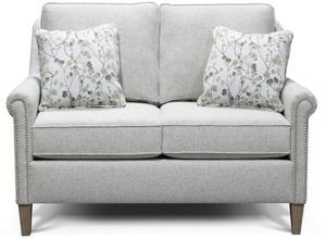 Light gray loveseat with nailhead trim and decorative pillows
