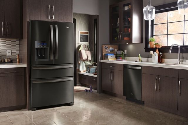 Black stainless steel refrigerator in a kitchen with dark wood cabinetry