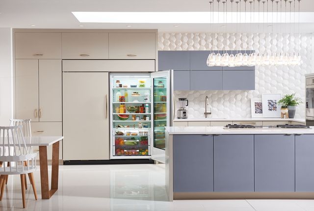 front view of a modern luxurious kitchen, paneled walls and appliances, with one opened refrigerator, and a beige and light blue color palette