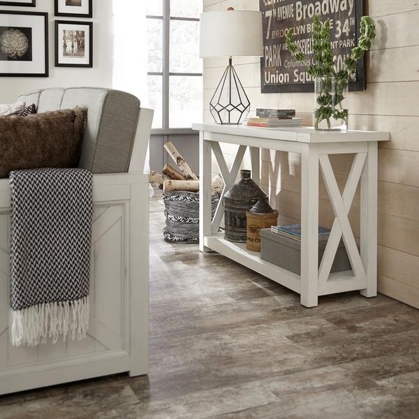 front view of a sofa table behind a sofa against a wall with various accents on it