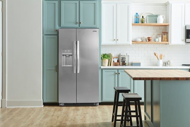 Stainless steel side by side refrigerator in a kitchen with blue cabinets