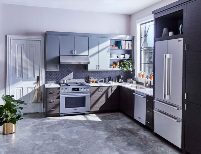 minimalist, modern, luxury kitchen with light grey walls, dark grey cabinets, and luxury appliances throughout