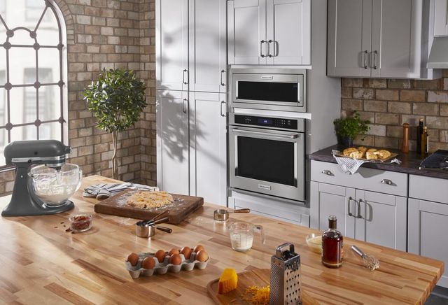 kitchen countertop with baking ingredients and an oven in the back surrounded by white cabinets