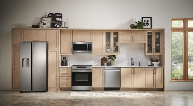 front view of a modern kitchen with light wooden cabinetry and stainless steel appliances