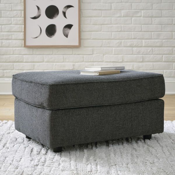 front view of a grey ottoman in front of a white brick wall with a moon phase artwork