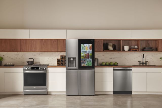 front view of a modern kitchen with beige cabinets and walls, and stainless steel samsung appliances, including a four door refrigerator