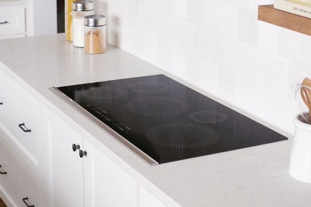 side view of a modern kitchen with white counters and a black glass cooktop