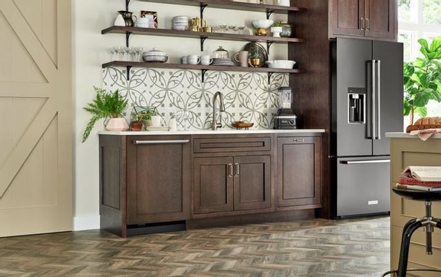 front view of a modern farmhouse kitchen with a dark brown panel dishwasher in the cabinets and a black stainless steel refrigerator