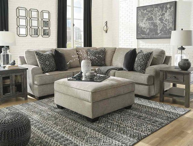 front view of a transitional living room with an l-shaped sectional, matching ottoman, and various decor throughout