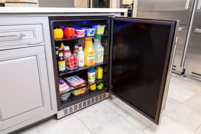 front view of an undercounter refrigerator in white cabients, open to show a stocked refrigerator