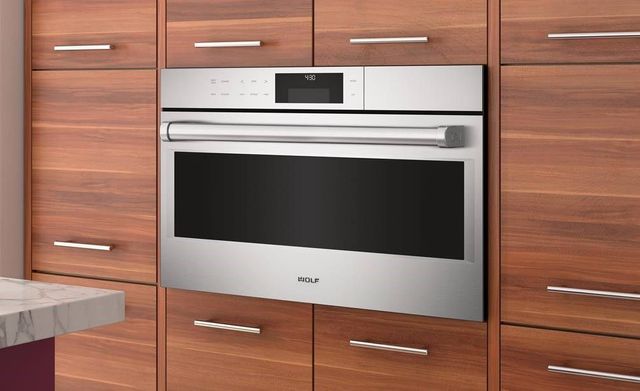 wolf oven built into red-brown cabientry with contemporary silver handles