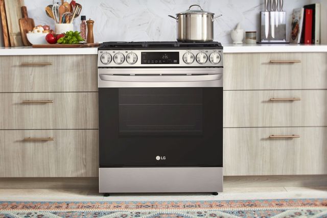 LG slide in gas range in a modern accessorized kitchen with a marble backsplash