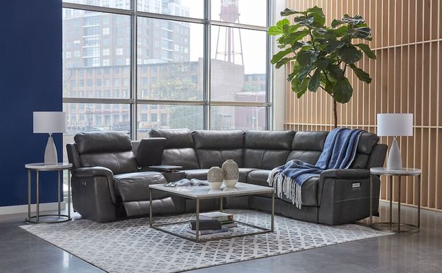 front view of a black leather reclining sectional in a modern living room with large windows and modern decor throughout