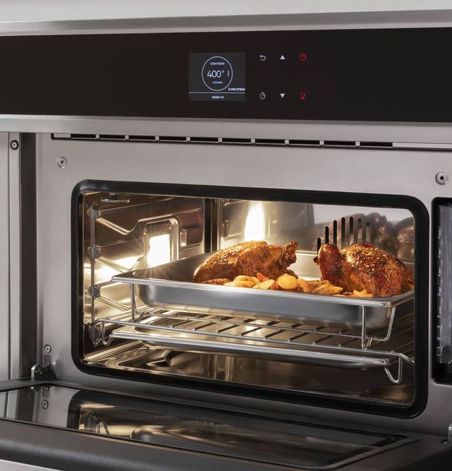 view of inside a steam oven cooking two small chickens and potatoes in a large pan