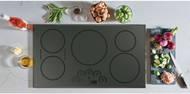 top view of a grey cafe cooktop in a marble countertop surrounded by various cooking ingredients like veggies, wine, oil, etc.