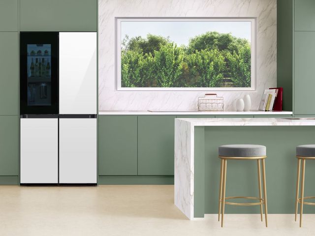 front view of a white samsung refrigerator in a modern minimalist kitchen with green cabinetry and marble countertops and backsplash
