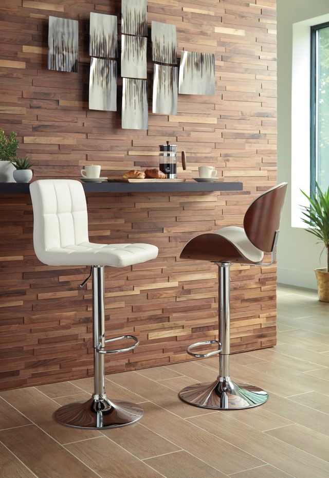 Two cream and wood bar stools in front of a stylish wood paneled wall