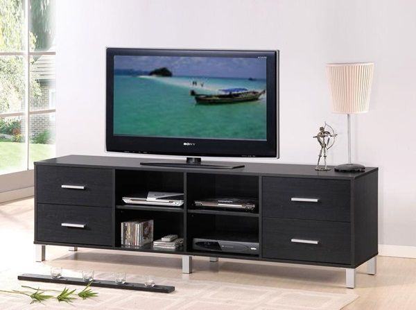 front view of a modern black tv stand with a tv, statue, and lamp on top, with miscellaneous items in the cubbies