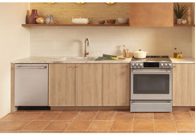 front view of a modern boho kitchen with light wood walls and backsplash, with a Cafe induction range between the light wood cabinets
