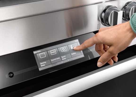 closeup view of a hand reaching for a touchscreen on a miele stove, showing some features and operating info