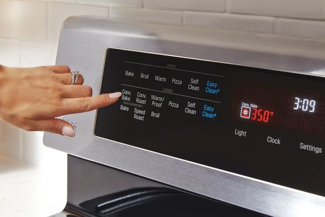 close up view of a hand pressing a setting button on an lg electric oven