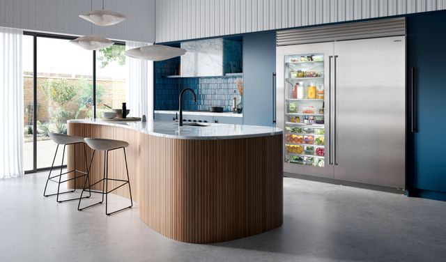 front view of a modern luxury kitchen, with an organic shaped island, with blue and white decor and two large sub zero refrigerators