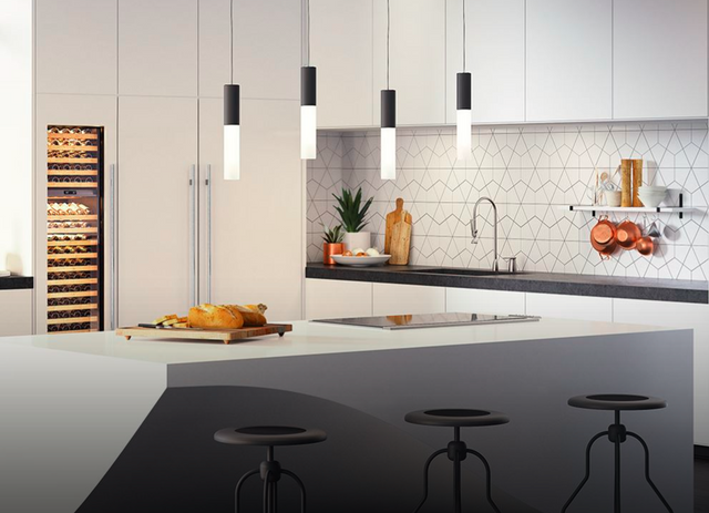 front view of a modern white kitchen with a 36" cooktop installed in the island and white panel ready appliances throughout
