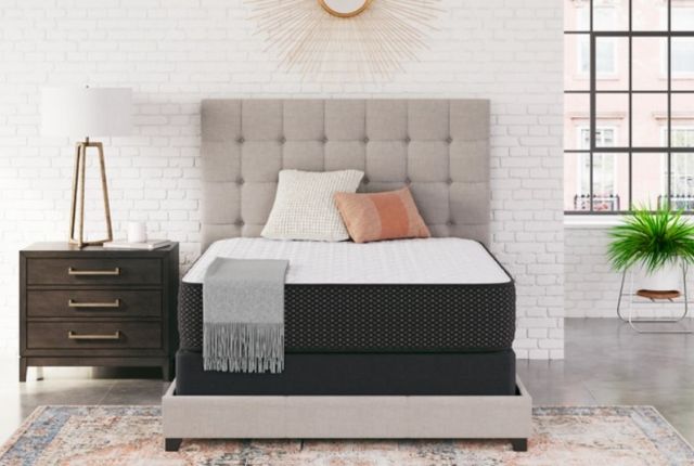 front view of a modern bedroom with white brick walls and a memory foam mattress on a grey upholstered bed frame