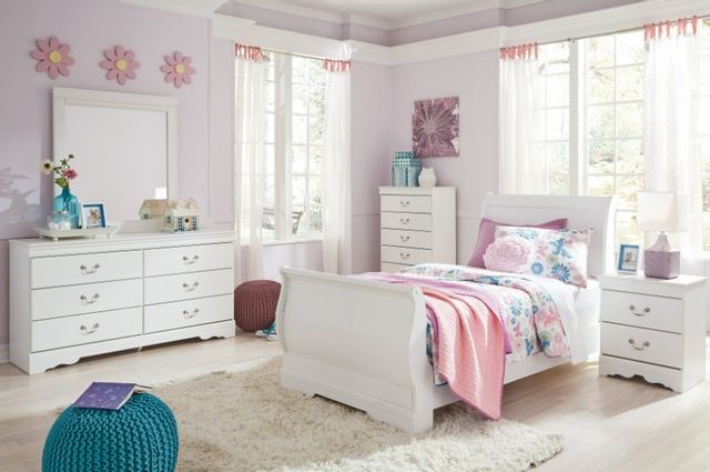 front view of a pink and white children's room with pink walls and a white twin bed, dresser, chest of drawers, and side table