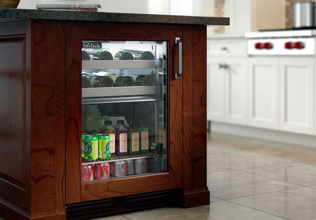 front view of the side of a brown kitchen island with a perlick undercounter refrigerator with a glass door showing stocked beverages 