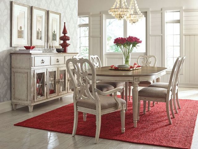 front view of a modern farmhouse dining room with light wood matching table, chairs, and dining hutch, with red accents throughout including a red rug and red flowers on the table