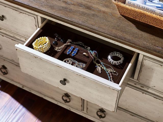 top view of a drawer, pulled out of a rustic dresser showing various jewelry inside