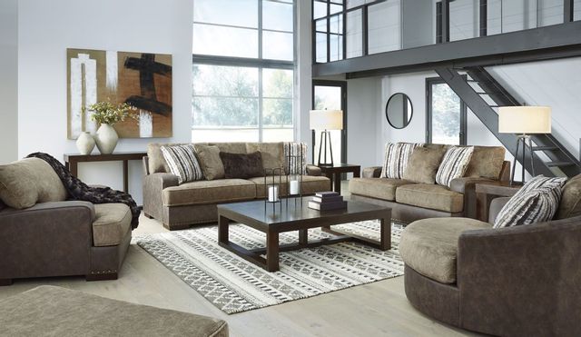 front view of a modern living room with two brown and black two-tone loveseats, and two matching oversized chairs on either side. The room has white walls and large floor to ceiling windows