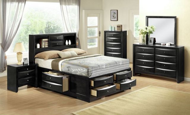 front view of a large bedroom with white walls, and a black storage bed with a matching end table, chest, and dresser