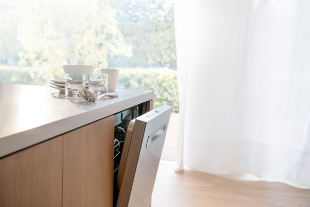 size view of a kitchen counter with a panel ready Bosch dishwasher slightly opened, with glassware on top of the counter