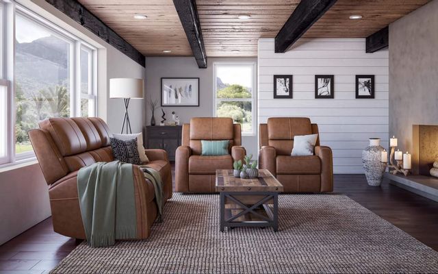front view of a modern living room with brown leather furniture and light green throw pillows and blankets. The furniture sits around a wooden coffee table and fireplace.