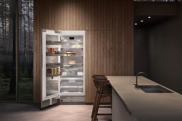 front view of an opened column refrigerator in a dark luxury kitchen with brown walls and an island in the foreground