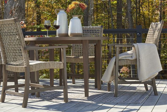 front view of a modern wood outdoor dining table with two wine glasses and decor, and the woods in the background