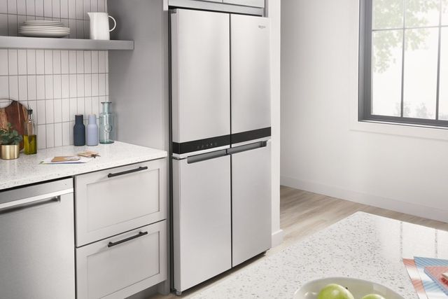 view of a stainless steel four door refrigerator in a modern white and grey kitchen