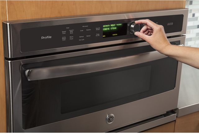 front view of a ge profile speed oven with a hand using the settings