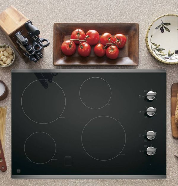 GE electric cooktop next to a set of knives and array of tomatoes