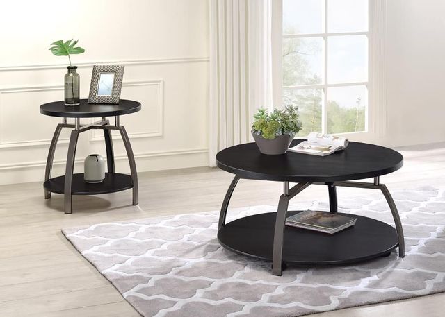 front view of a contemporary black round coffee table and matching side table with accent decor on top in a modern living room corner with white walls and grey floors