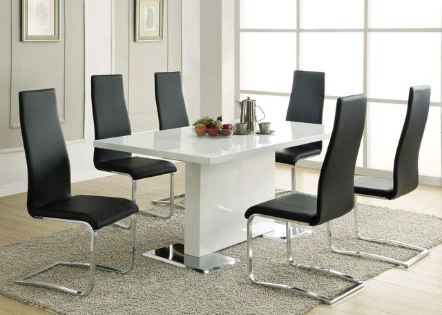 large white regtangular pedestal dining table surrounded by sleek black seats in a bright white dining room