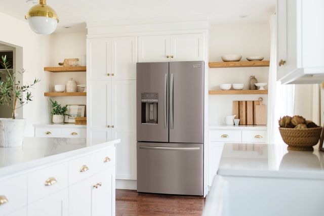 front view of a modern white kitchen with a stainless steel french door refrigerator centered 