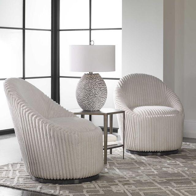side view of two white contemporary upholstered accent chairs around a side table and matching lamp
