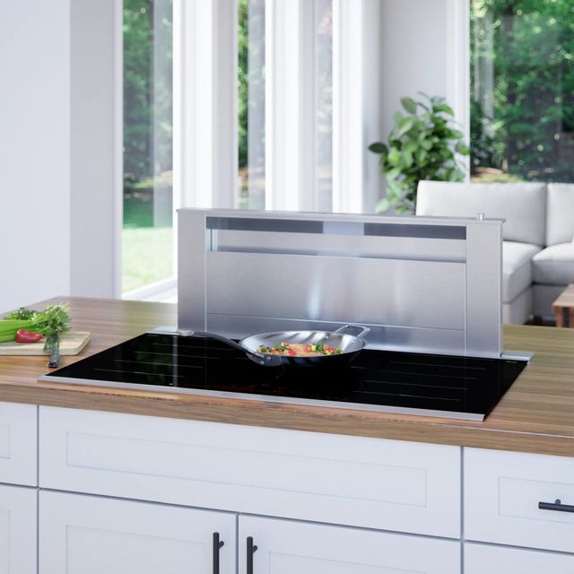 front view of a bosch induction cooktop in a wooden countertop with ventilation and windows in the background