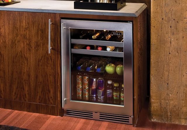 front view of an undercounter refrigerator in brown counters with a clear glass door showing a stocked beverage fridge