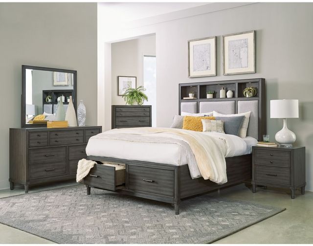 view of a modern bedroom with grey furniture and a queen storage bed with the foot drawer slightly pulled out with a blanket hanging out